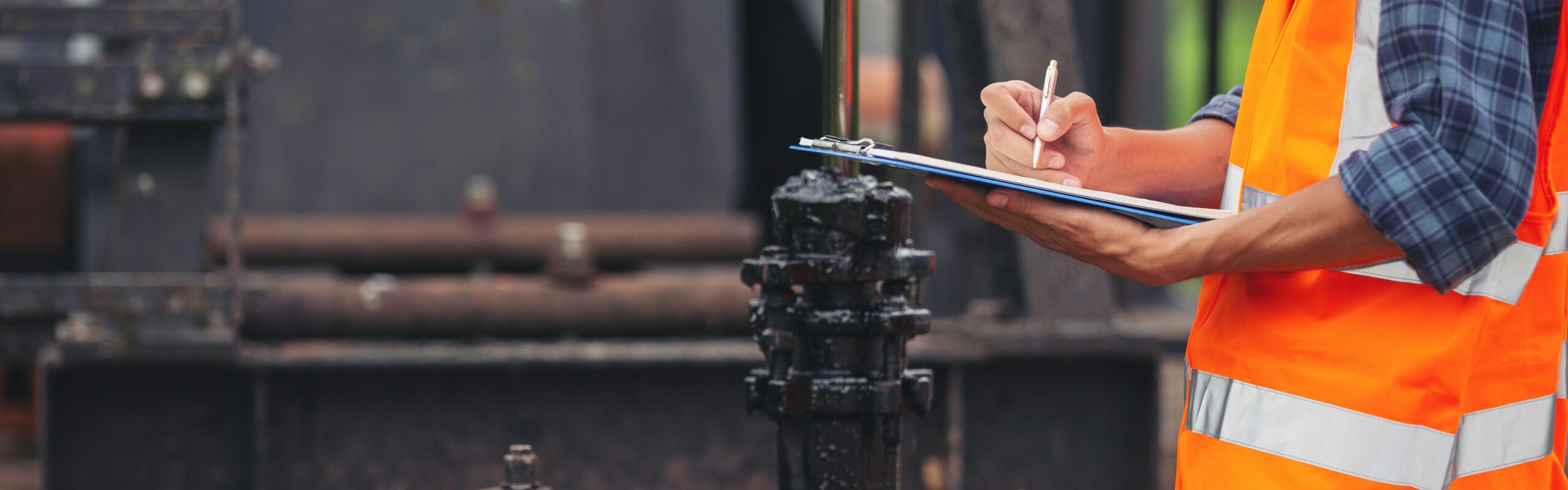 Workers standing and checking beside working oil pumps.